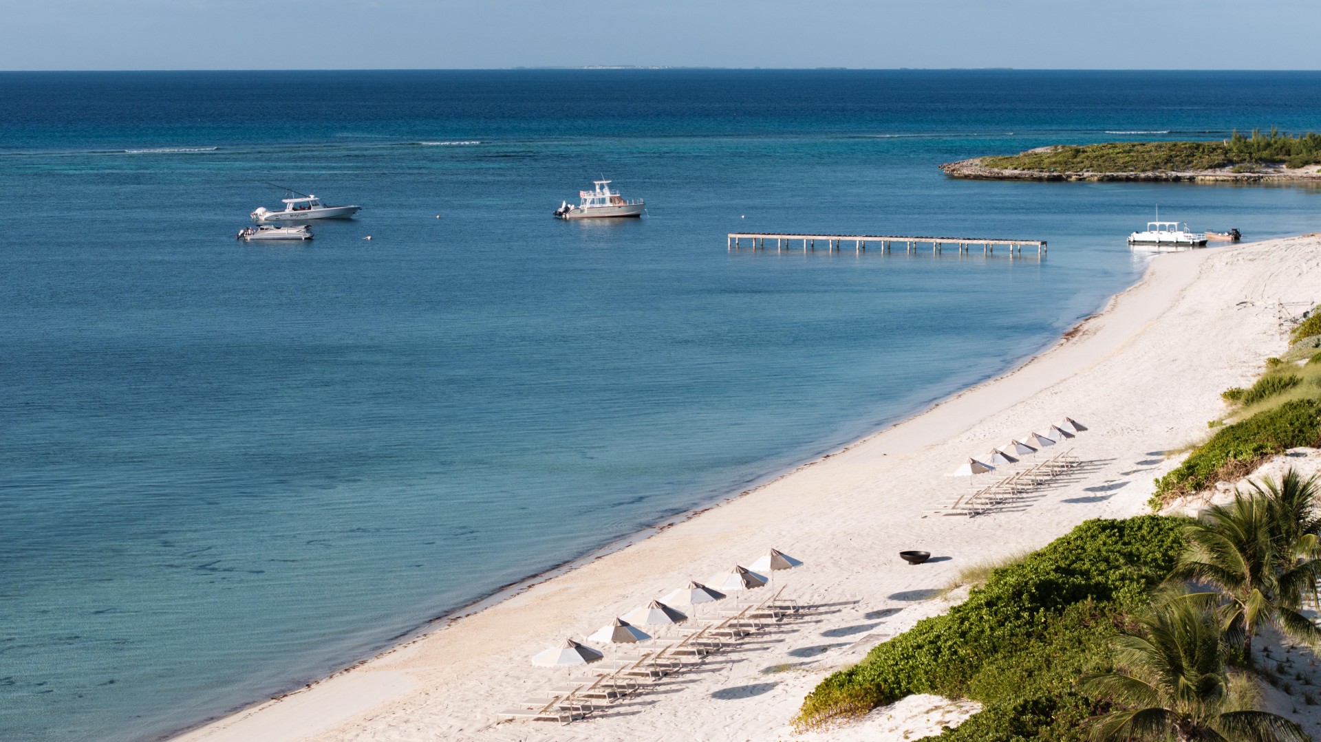 a beach with umbrellas and boats in the water