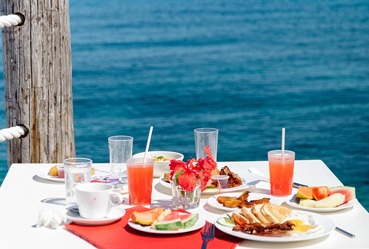 casual breakfast table with fruit, juice, toast set on table on patio with ocean view
