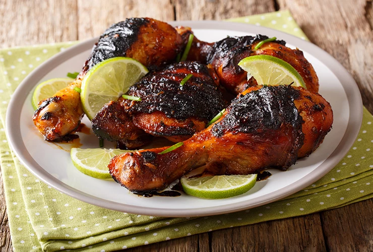 roasted chicken legs with lime wedges on plate