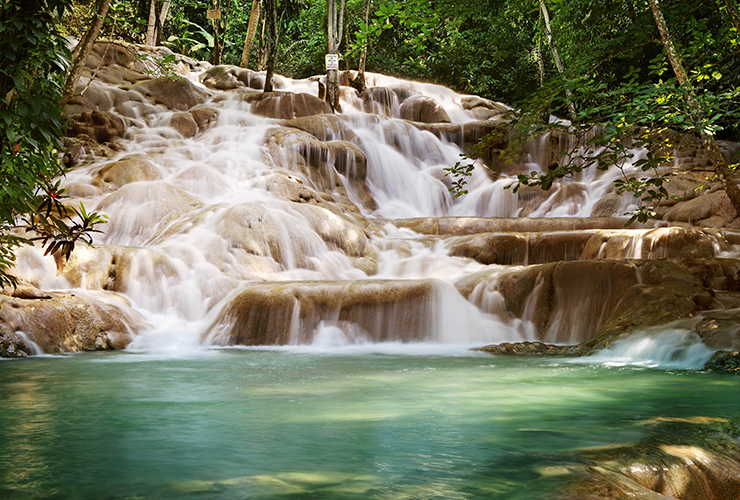 natural waterfall cascading down layered rocks into clear blue water