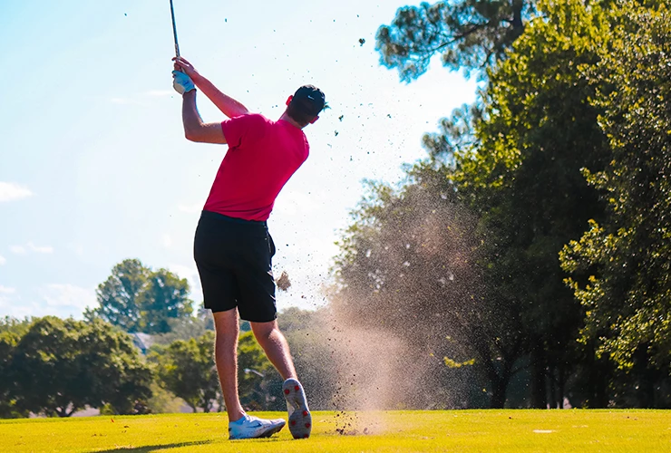 male golpher at the top of his swing on a great open course