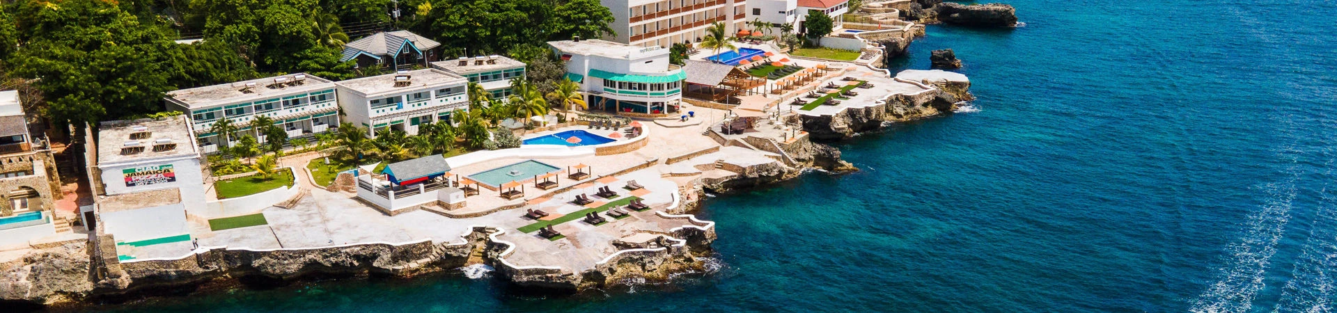 aerial view of resort buildings with ocean, pools, and cabannas