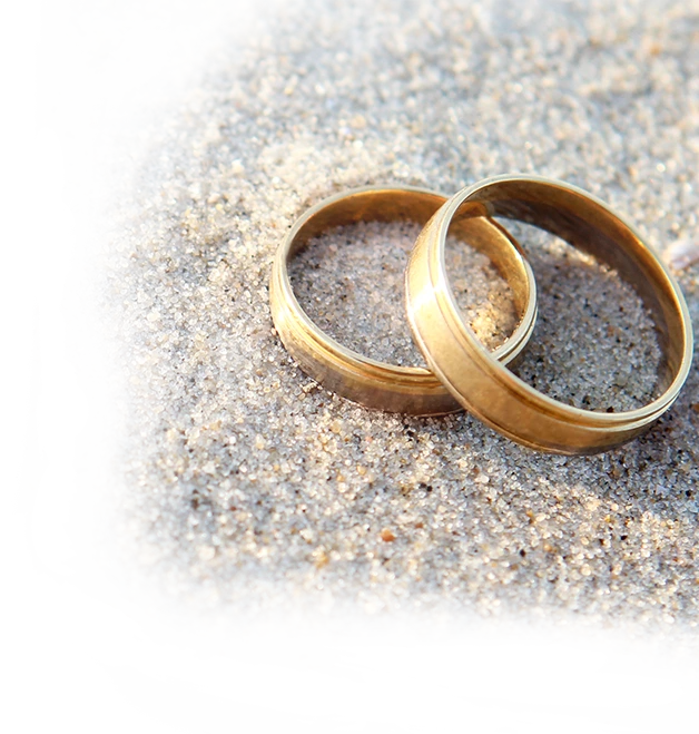 close up of wedding bands overlapped on one another set on sand