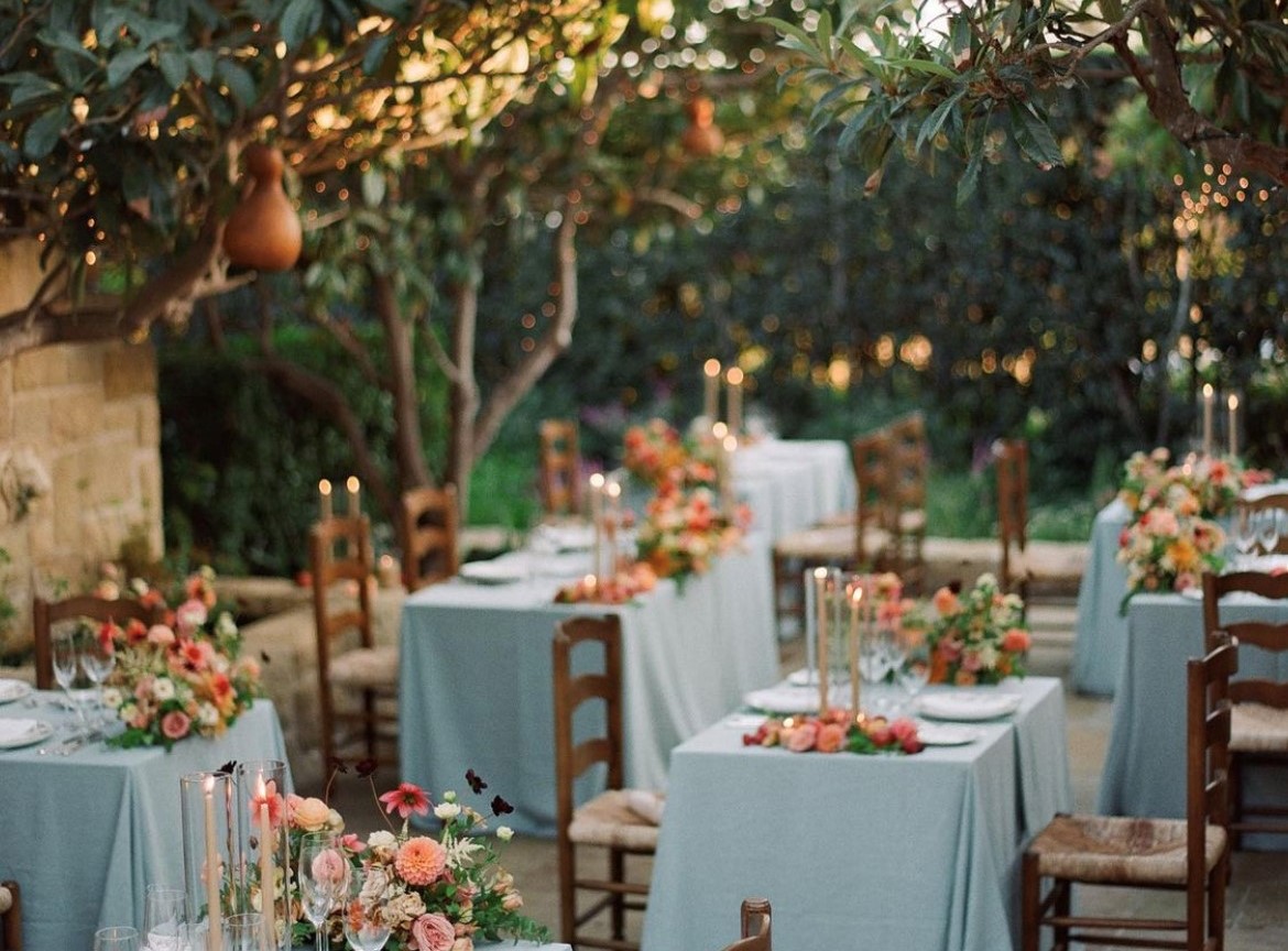 a set of tables with chairs and tables under a tree