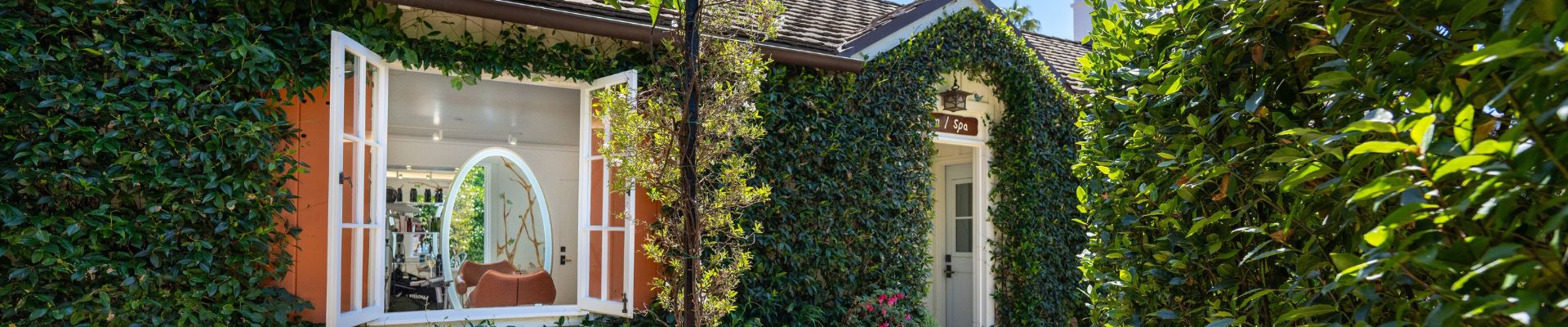 exterior of cottage inspired salon and spa with greenery on the outside