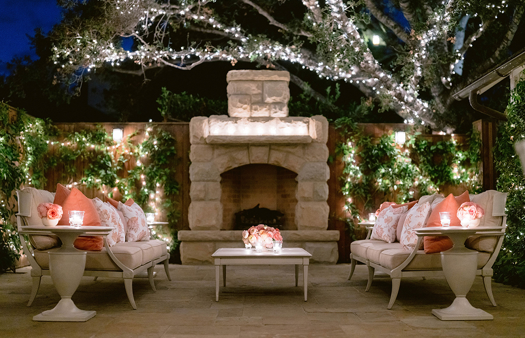 a patio with white furniture and a fireplace
