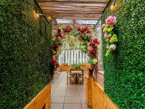 a walkway with a table and chairs and a flower arch