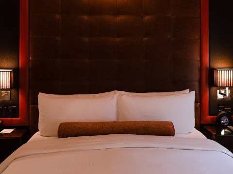 a bed with white sheets and a brown pillow