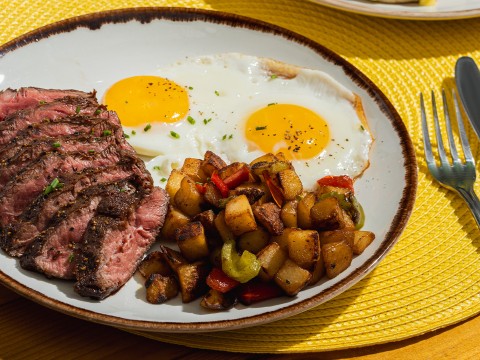 a plate of steak and eggs with potatoes