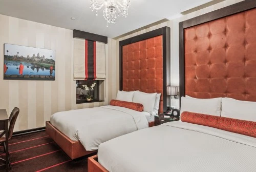 A hotel room with two beds, tufted headboards, and a chandelier