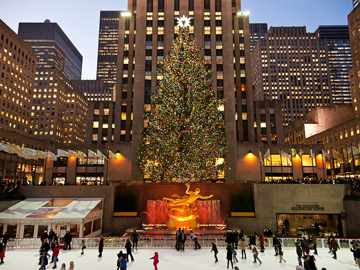 a large tree with lights and people skating on ice