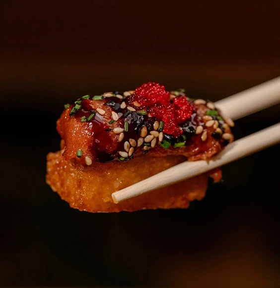 a piece of food with sesame seeds and sauce on top