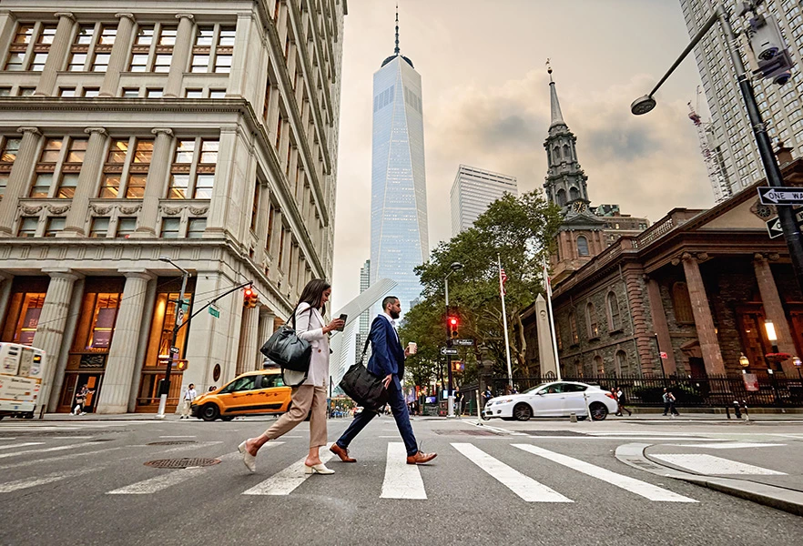 a city street with people walking across a crosswalk
