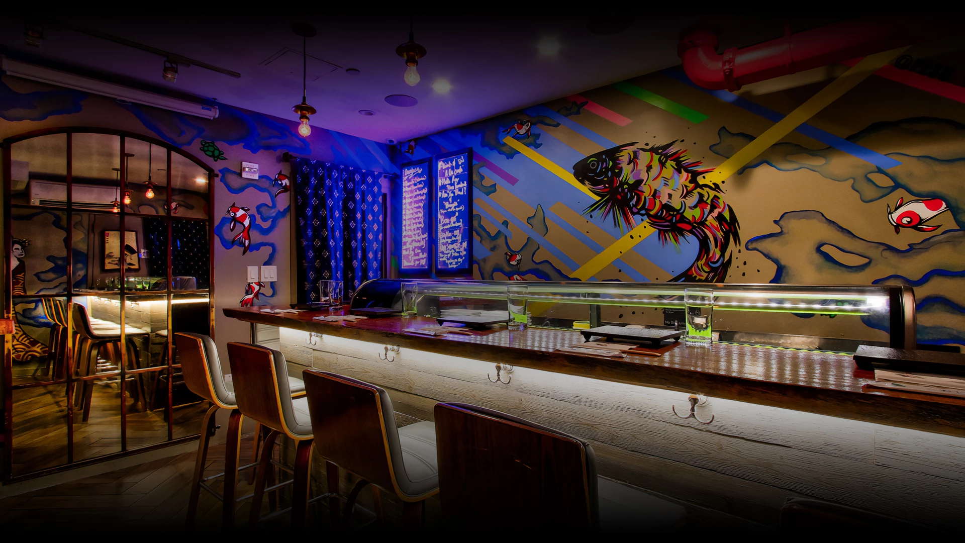 a bar with a colorful mural on the wall