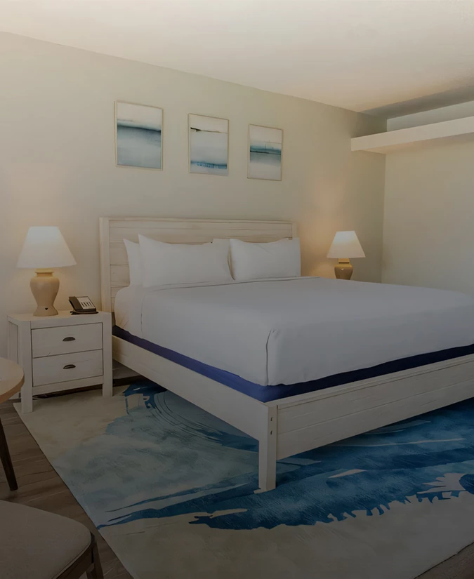 A hotel room with a large bed, two nightstands, and three ocean-themed pictures on the wall.