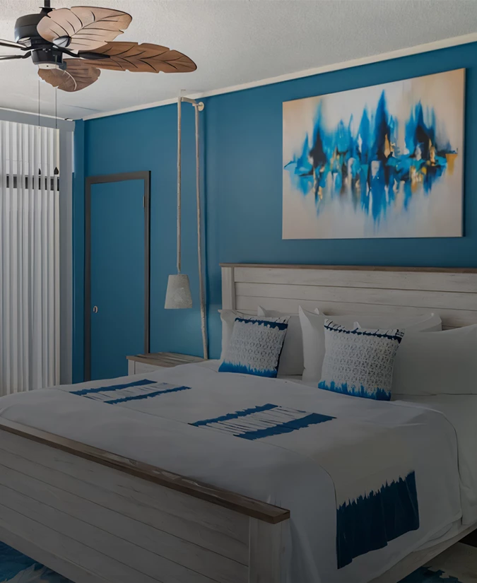 A guest bedroom with a large bed, blue walls, and abstract art.