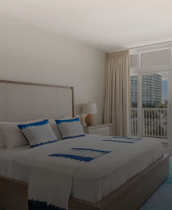 A hotel room with a large bed, a window, and a balcony with a city view.