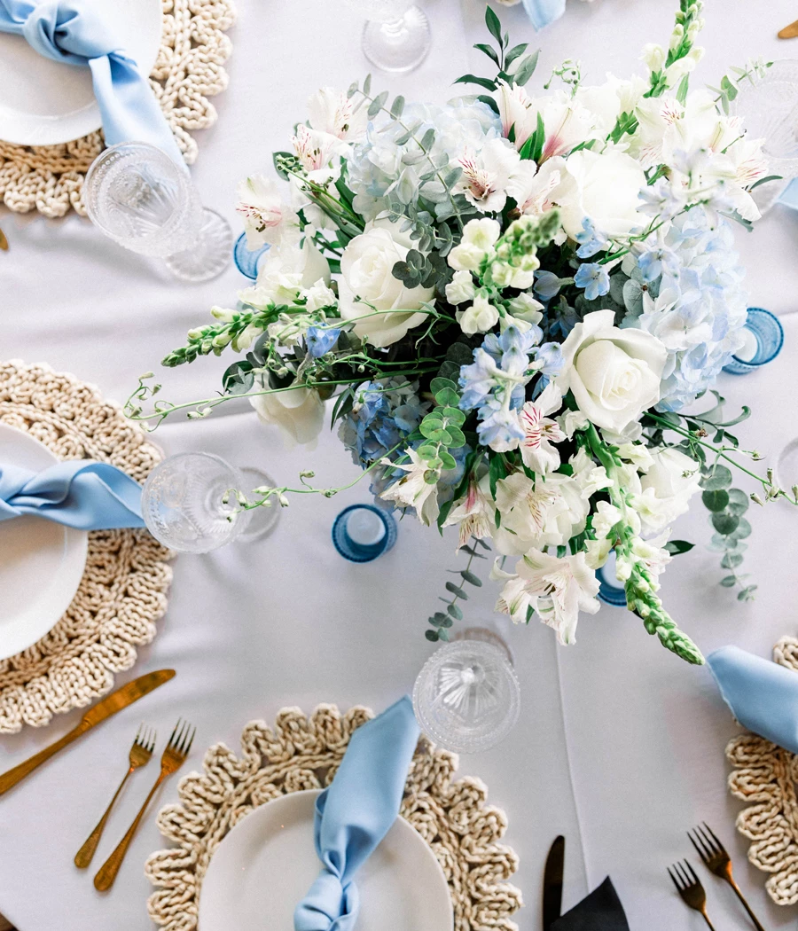 a table set with white plates and blue napkins