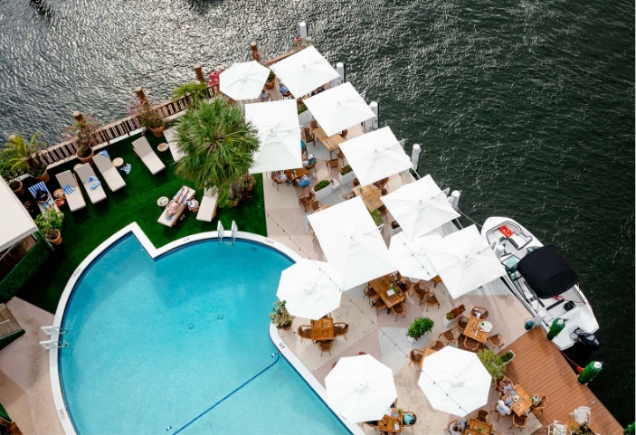 a pool with umbrellas and tables by a body of water