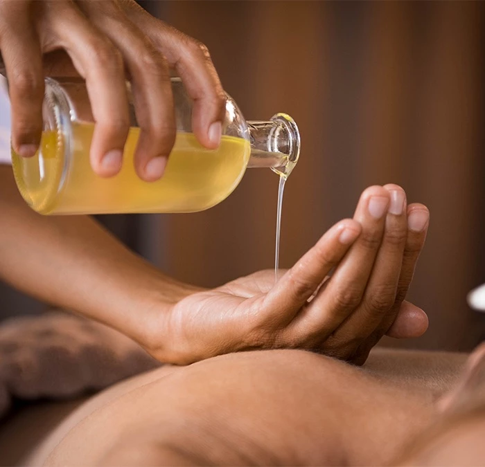 spa employee pouring massage oil onto hands