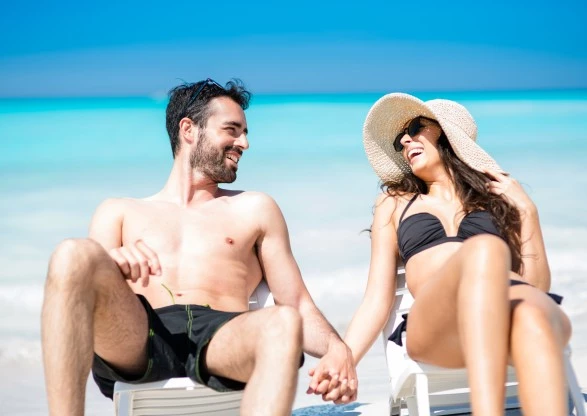 a man and woman sitting in chairs on a beach
