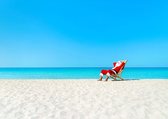 a santa claus sitting in a chair on a beach