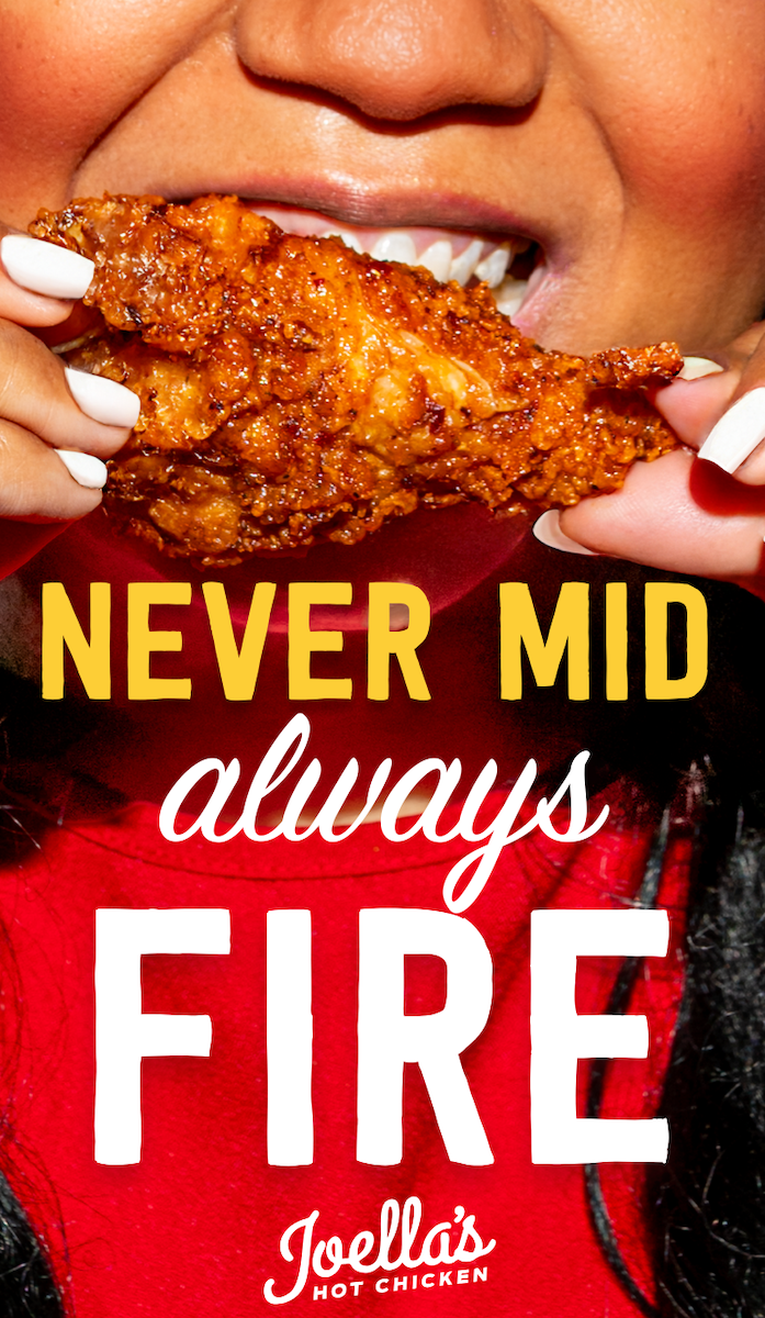 a person holding a piece of fried chicken