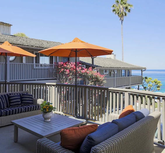 a patio with a table and chairs and an orange umbrella