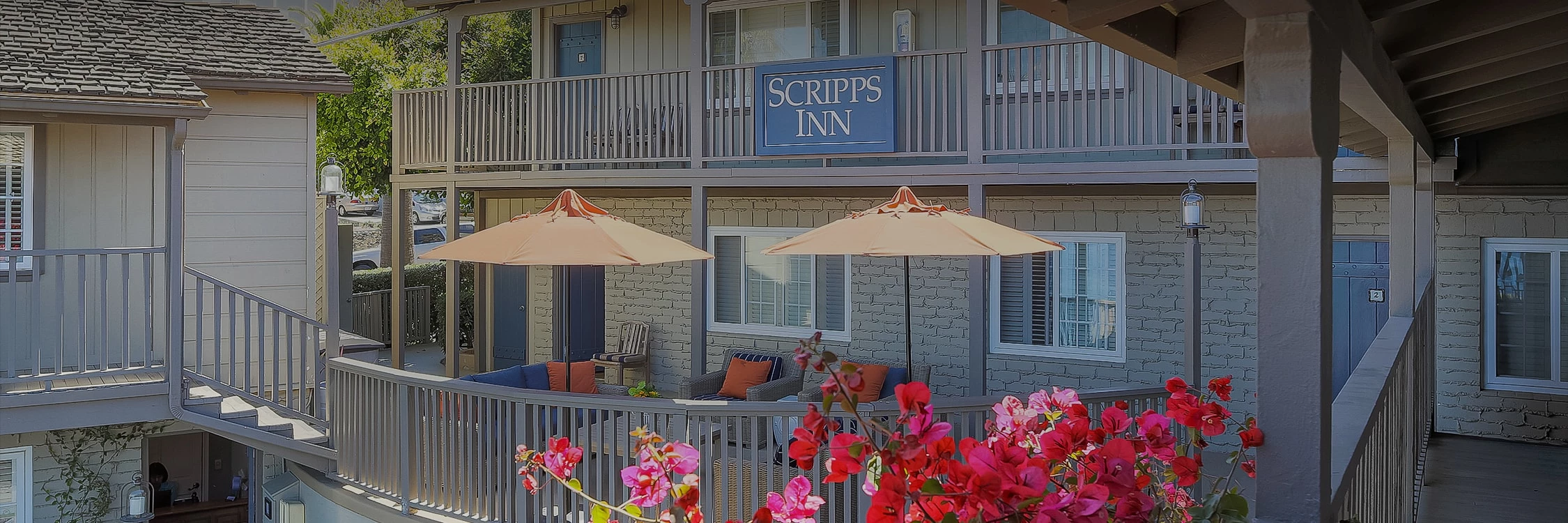 a patio with umbrellas and chairs surrounded by flowers