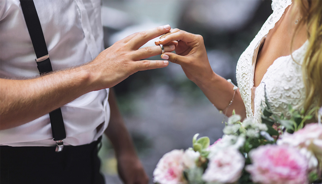 bride putting ring on grooms finger