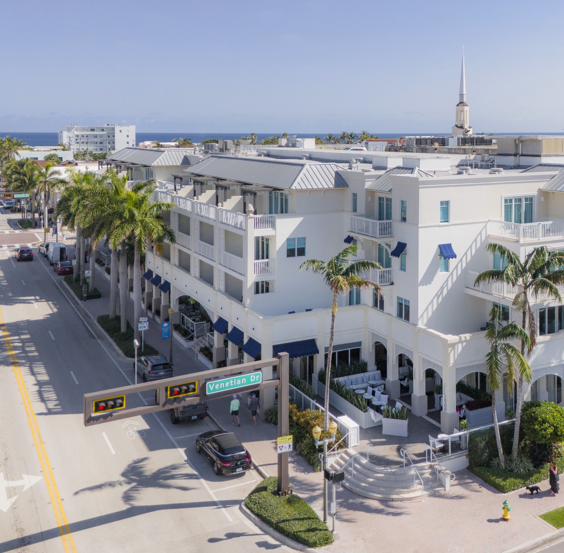 a white building with palm trees and a street
