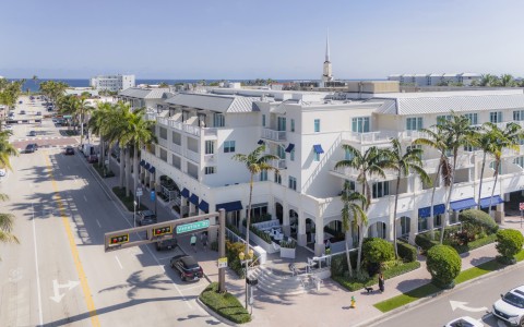 a white building with palm trees and a street sign