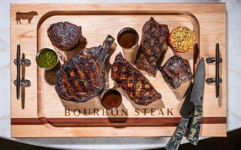 a wooden cutting board with steaks and sauces