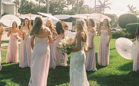 a group of women in white dresses holding umbrellas