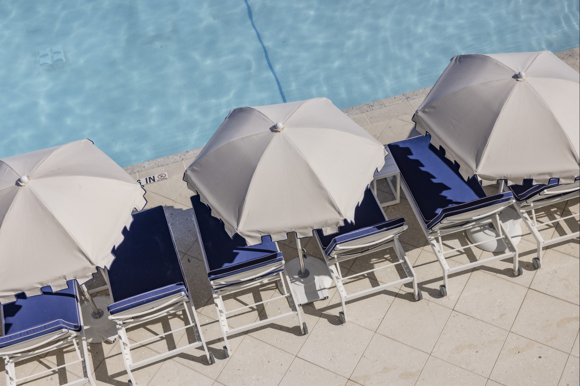 a group of chairs and umbrellas by a pool