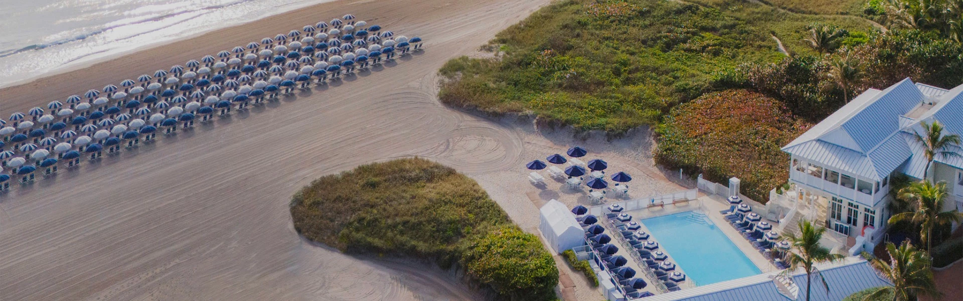 an aerial view of a beach with umbrellas and chairs