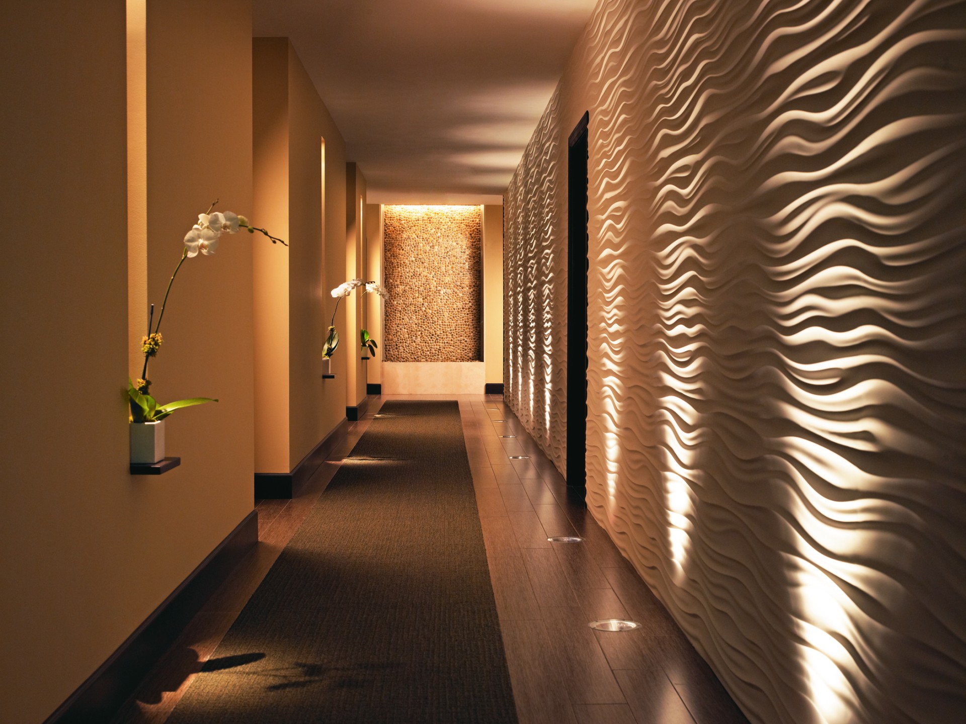 a long hallway with a wall and a flower pot