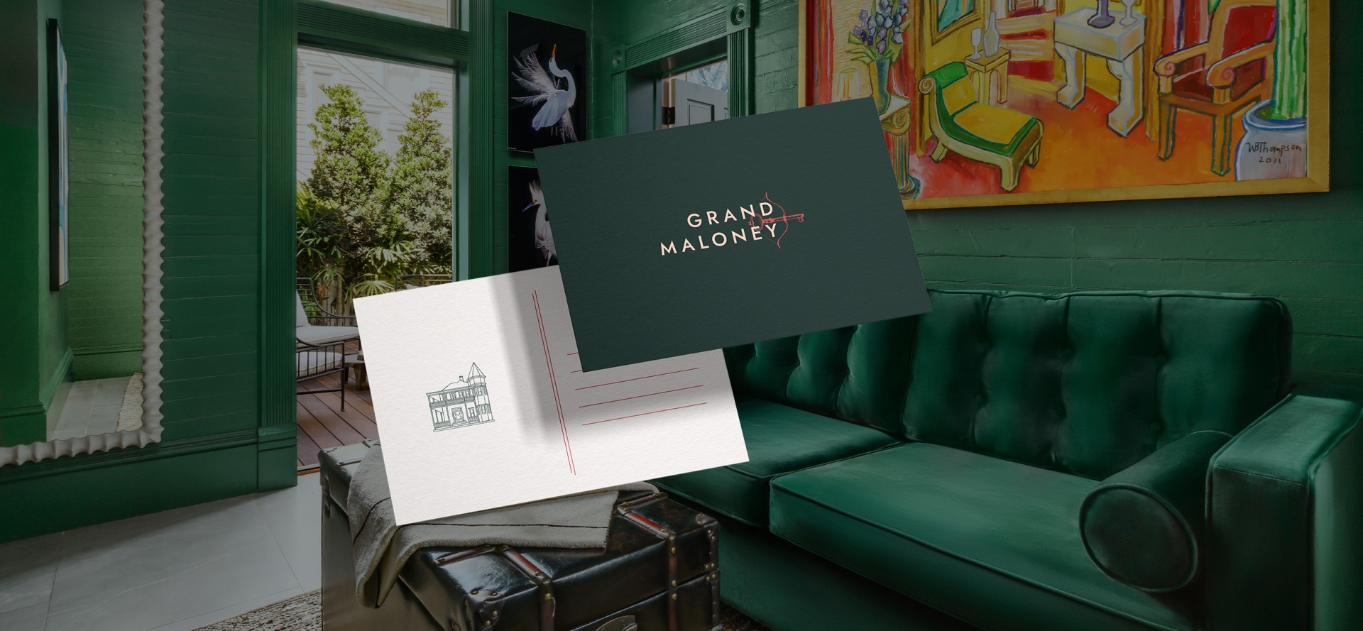 a postcard with The Grand Maloney Branding & logo on it with a picture of a room in the background