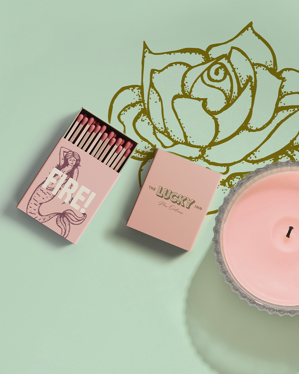 a box of matches next to a candle with the Lucky Inn branding and logo on the packaging