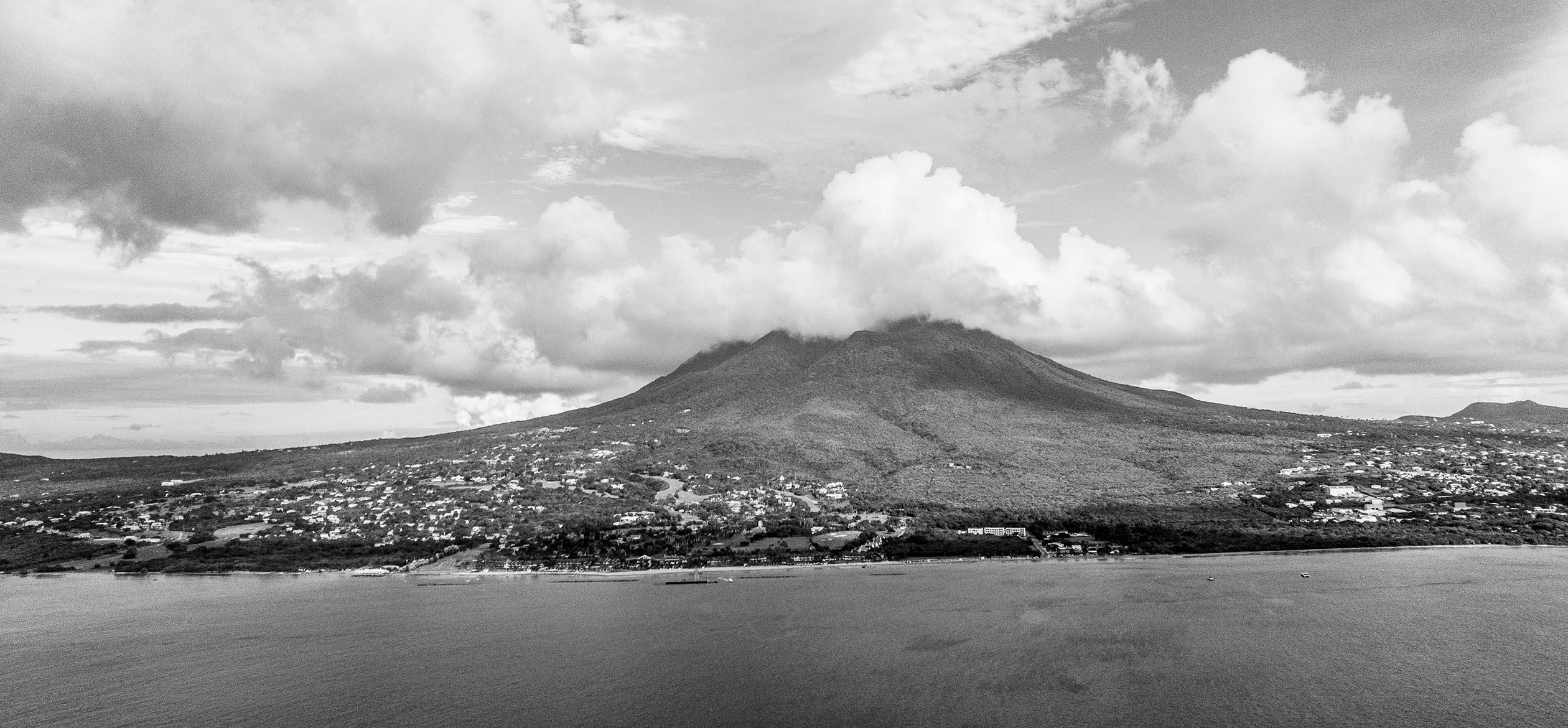 a mountain with a body of water and clouds