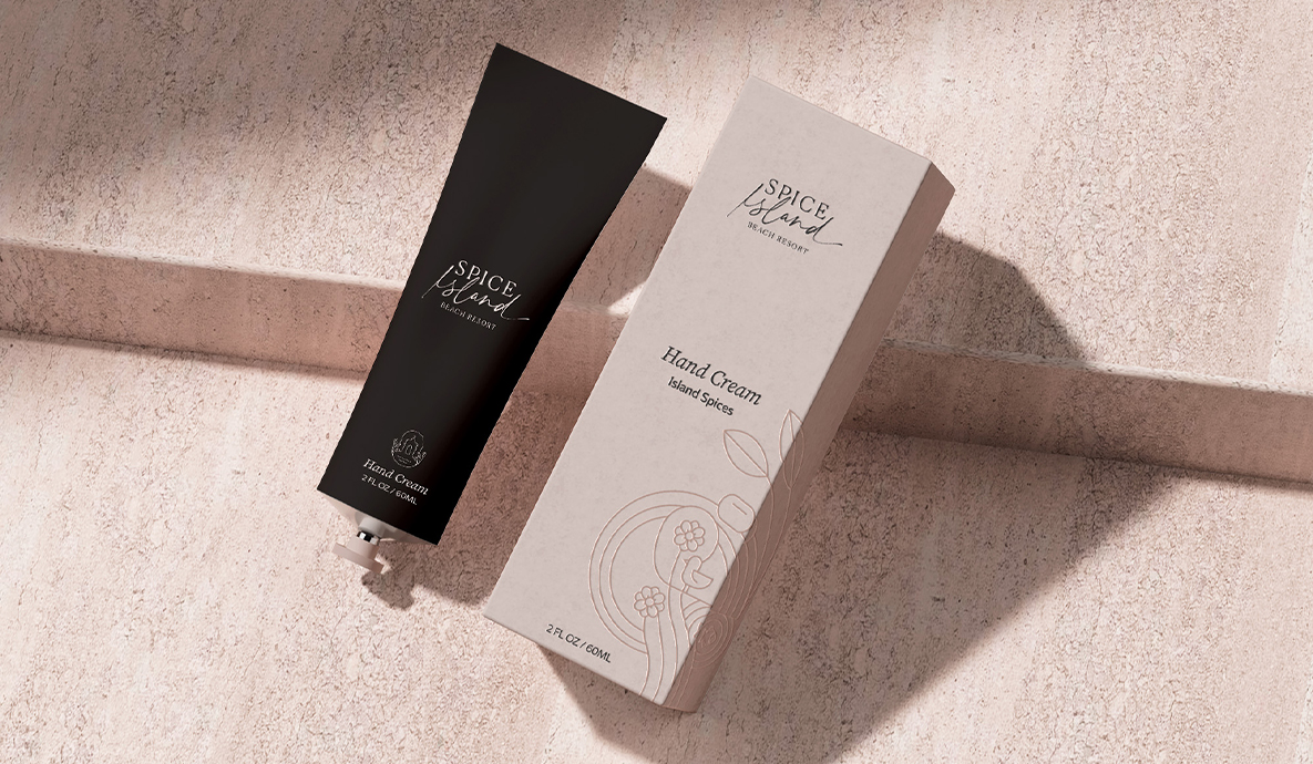 a black tube of hand cream next to a white box with spice island logo on them