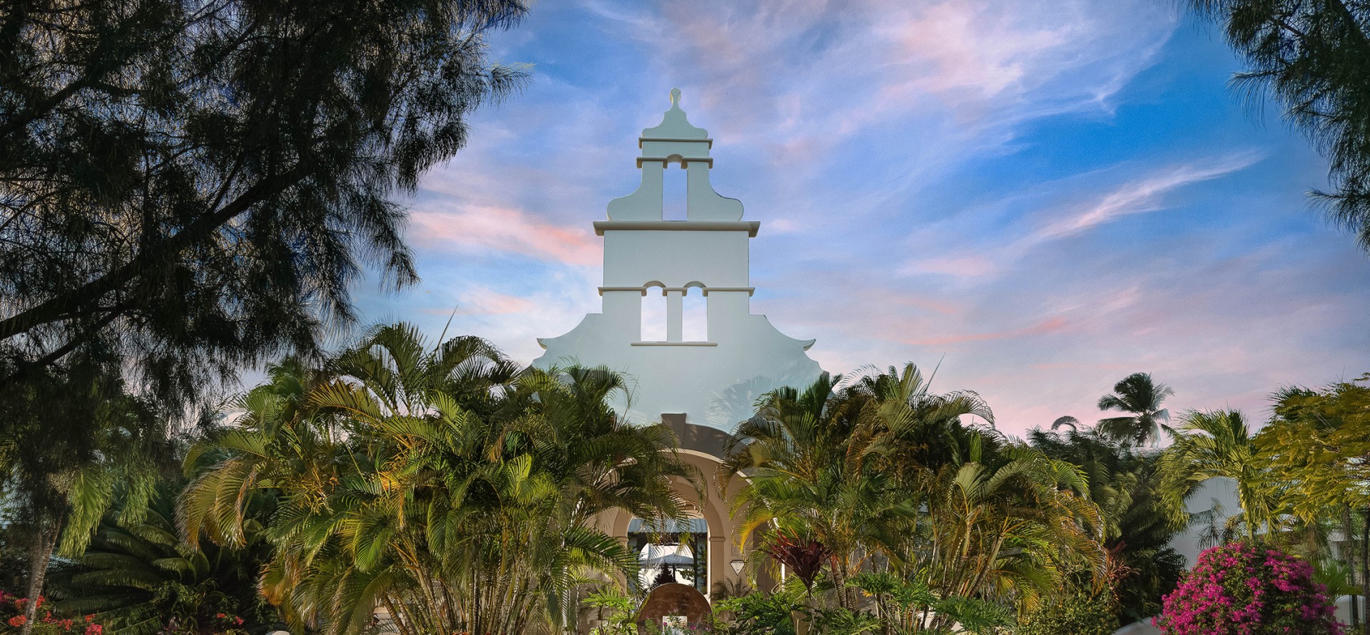 a white building with a tower and palm trees