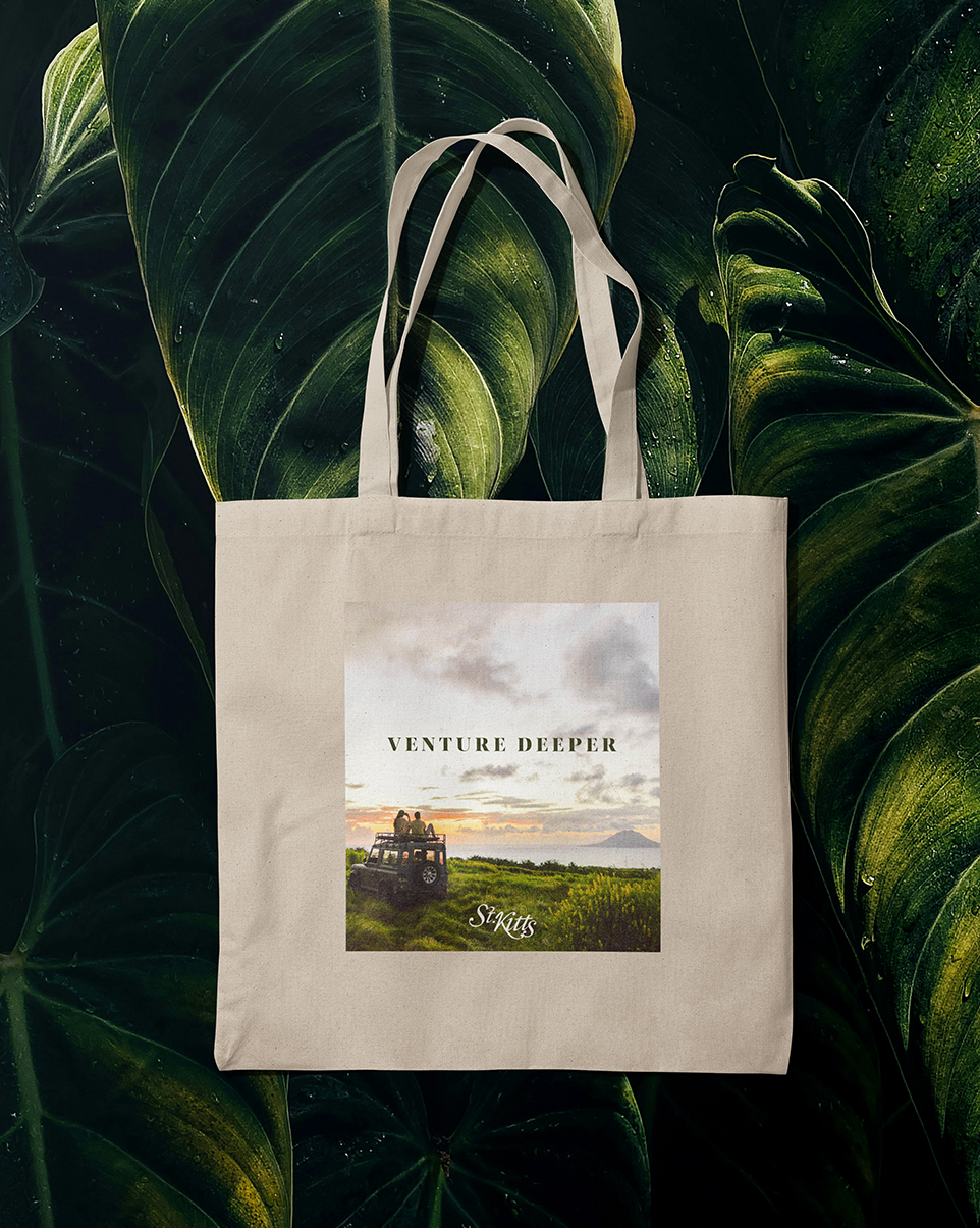 a tote bag with a picture of a truck and people at a scenic overlook with st. kitts logo on it