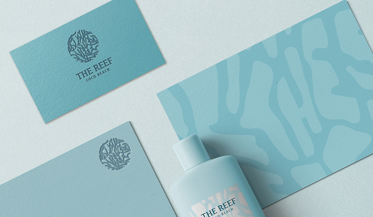a bottle of lotion next to branded post cards with The Reef logo