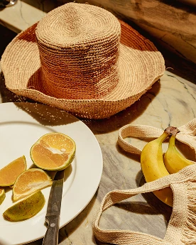 a straw hat and fruit on a plate