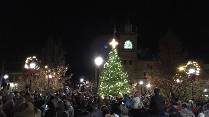 a crowd of people in front of a christmas tree