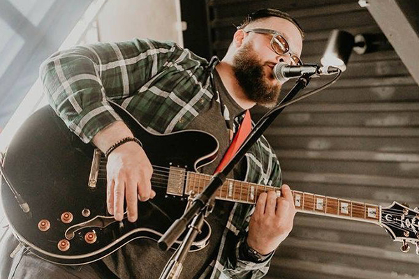 Adam McKinley playing guitar and singing into a microphone