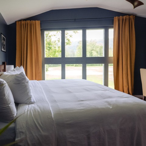 a bed with white sheets and orange curtains