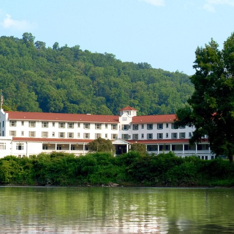a large white building with red roofs and a red roof next to a body of water