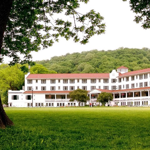 a large white building with red roof and a large lawn